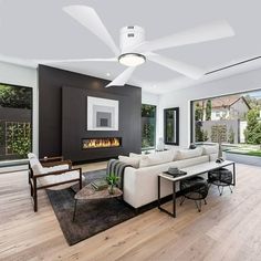 a modern living room with wood floors and white furniture in front of large windows that look out onto the backyard