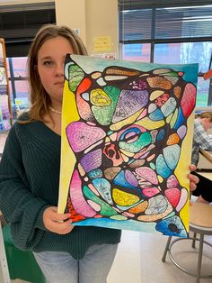 a woman holding up a painting in front of her face