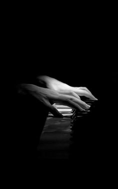 black and white photograph of hands on top of a computer keyboard in the dark,