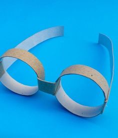 a pair of goggles made out of paper on a blue background with the text how to make eyeglasses out of toilet paper