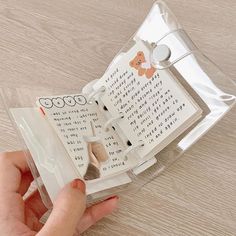 a person holding an open book on top of a wooden table