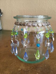 a glass jar filled with lots of different colored beads and chains on top of a table