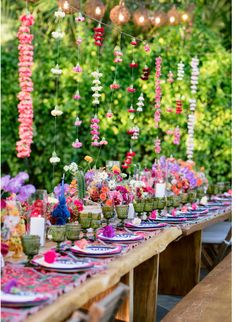 a long table with plates and flowers on it is set for an outdoor dinner party