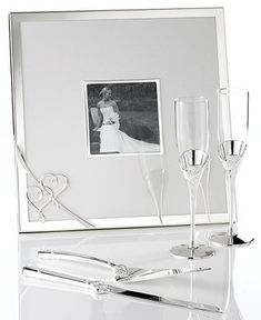 two champagne flutes and a wine glass in front of a photo frame with the bride and groom on it