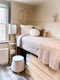 a bed sitting next to a window with pillows on top of it in a bedroom