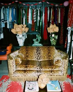 a leopard print couch sitting in front of a closet filled with clothes and vases