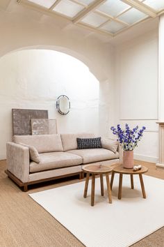 a living room with a couch, coffee table and mirror on the wall next to it