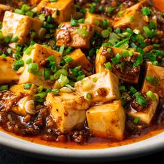 a white plate topped with tofu and green onions