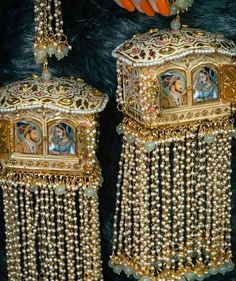 a pair of gold - plated earrings with paintings on them are being held by a woman's hand