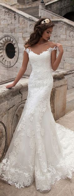 a woman in a wedding dress leaning on a stone wall