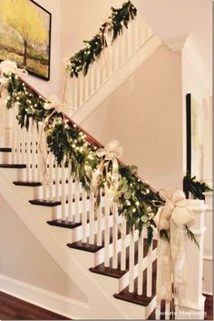 the stairs are decorated with greenery and white ribbon for garlands on each handrail