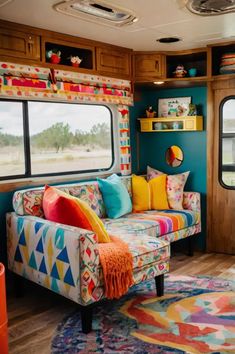 a colorful couch in front of a window with lots of pillows on top of it