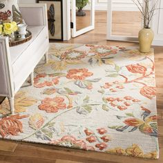 a white rug with orange and yellow flowers on it in a living room next to a couch