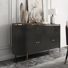 a black and gold sideboard in a white room with a painting on the wall