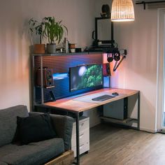 a computer desk with a monitor and keyboard on it in front of a wall lamp