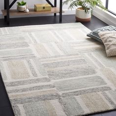 a white rug with squares on it in front of a table and potted plant