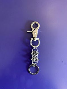 a metal keychain hanging on a purple wall