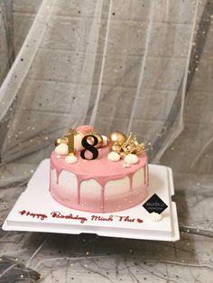 a pink and white birthday cake with gold decorations