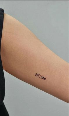 a woman's arm with the word home tattooed on her left arm, in black ink