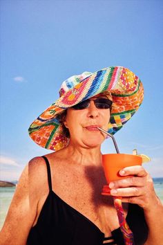 a woman with a straw hat drinking from an orange cup