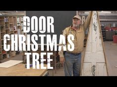 a man standing next to a wooden christmas tree