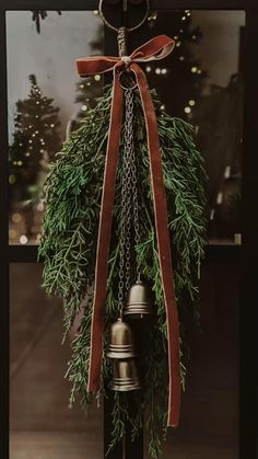 a bell with a bow hanging from it's side next to a christmas tree