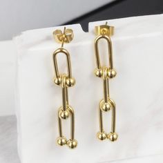 Introducing our stunning Emma U-Shaped Earrings, a unique and stylish accessory that is sure to make a statement. These earrings feature a beautiful and intricate design that is both contemporary and classic, making them perfect for any occasion. Crafted from high-quality materials and plated with 14K gold, these earrings are both beautiful and durable. The gold plating gives them a luxurious and sophisticated look that is sure to catch the eye of anyone who sees them. They are also incredibly l Elegant Gold Earrings With Unique Design, Modern Pierced Chandelier Earrings As Gift, Modern Gift Chandelier Earrings, Elegant Dangle Earrings With Unique Design, Statement Earrings Gold, Gold Statement Earrings, Intricate Design, Stylish Accessories, Earrings Gold