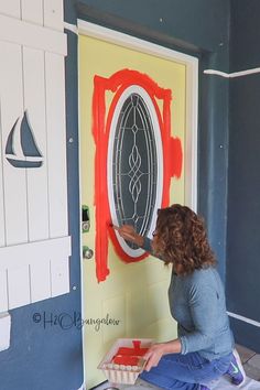 a woman painting a door with red paint