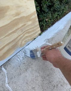 a man is painting the outside of a house with white paint and wood planks