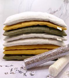 a stack of different colored pillows next to a rolling pin