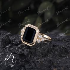 a black diamond ring sitting on top of a rock with diamonds around it's edges