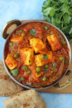 tofu curry in a bowl with pita bread and cilantro on the side