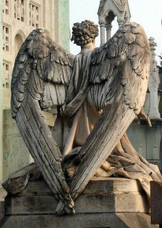 an angel statue holding a heart in front of a building