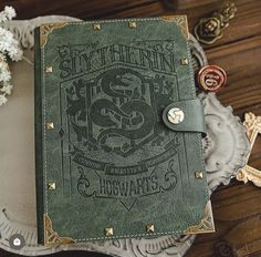 a green leather book sitting on top of a white plate next to flowers and other decorations