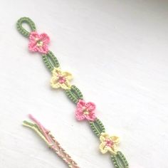 two crocheted bracelets with pink and yellow flowers on them sitting next to each other