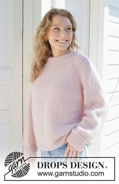 a woman wearing a pink sweater standing in front of a white door with her hands on her hips