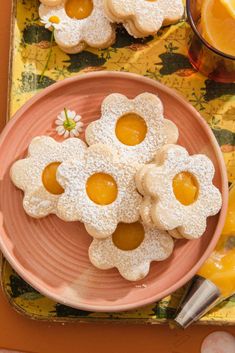 some cookies are on a pink plate next to oranges and lemon wedges in the shape of flowers