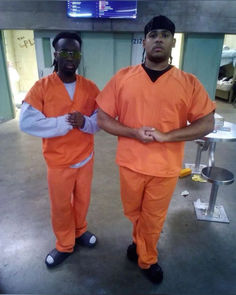 two men in orange prison uniforms standing next to each other