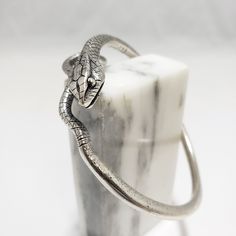 Make a bold statement with this wrap around snake bracelet. This bracelet is adjustable pewter with a silver-plated finish. High-quality finish designed to last! Special care should be taken when opening and closing the bracelet so that it does not become misshapen. This beautiful bracelet will ship in a jewelry box.  Made in the USA In ancient Egypt, as in many cultures, snakes were both feared and worshiped. As one of the demons of the underworld, the destructive Apophis was feared while the serpent Meretsger was worshiped as the protector of the Valley of the Kings. A cobra, uraeus, was attached to the headdress of King Tutankhamen and the other rulers as their royal insignia and the protection. Also, some believe that Cleopatra was killed by a snake that she had smuggled into her room. Royal Insignia, Wrap Around Snake, Make Way For Ducklings, The Serpent, Valley Of The Kings, Snake Bracelet, King Tut, The Underworld, The Kings