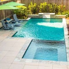 a small pool with lounge chairs and umbrellas next to the side of it in a backyard