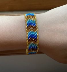 a woman's arm wearing a blue and gold beaded bracelet