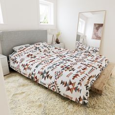 a bed sitting on top of a white rug next to a dresser and mirror in a bedroom