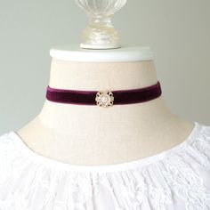 This elegant choker necklace is handmade with a soft velvet ribbon in a rich eggplant purple hue. It features a sparkling gold tone rhinestone and pearl center jewel. A one-of-a-kind gift for a friend who loves unique jewelry! Also available with a teal blue velvet ribbon, sold separately in the Rosy Posy Designs shop.  * Length ~ 12 inches + 3 inch extender (fits a 12-15 inch neck size)  * Band ~ 1/2 inch wide velvet band * Fastens with lobster clasp * Ships in a pretty gift box Discover more o Elegant Burgundy Jewelry For Party, Elegant Burgundy Party Jewelry, Purple Choker Necklace For Gift, Elegant Purple Wedding Choker, Adjustable Burgundy Jewelry For Party, Adjustable Purple Choker For Party, Elegant Purple Choker Jewelry, Jewel Choker, Blue Velvet Ribbon