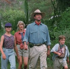 three adults and two children are walking in the woods together, one is wearing a hat