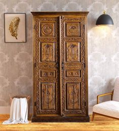 an ornate wooden armoire in the corner of a room with a chair and wallpaper