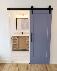 an open door leading to a bathroom with wooden floors and white walls, is shown