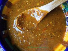 a wooden spoon sitting in a bowl filled with brown liquid and spices on top of it