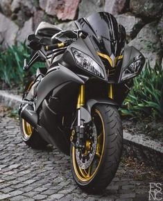 a black and yellow motorcycle parked on the side of a road next to some rocks