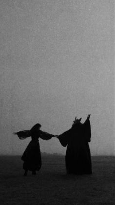 two women are holding hands in the middle of an open field with a kite flying overhead