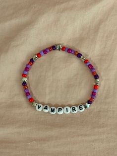 A hand-crafted glass bead friendship bracelet highlighting Olivia Rodrigo's song "Vampire"! A simple and cute way to show off your favorite song or a great concert accessory!  This bracelet is made with Czech glass beads, plastic letter beads, plastic spacer beads, and is on an elastic thread measured at about 10 inches in length for a relaxed/loose fit. If you would like the bracelet you order to be smaller or larger, please leave the requested size in inches in the personalization box!  All br Olivia Rodrigo Friendship Bracelet, Olivia Rodrigo Bracelets, Song Bracelets, Bead Friendship Bracelet, Olivia + Core + Aesthetic, Holiday Bracelets, Guts Tour, Friendship Bracelets With Beads, Purple Bracelet